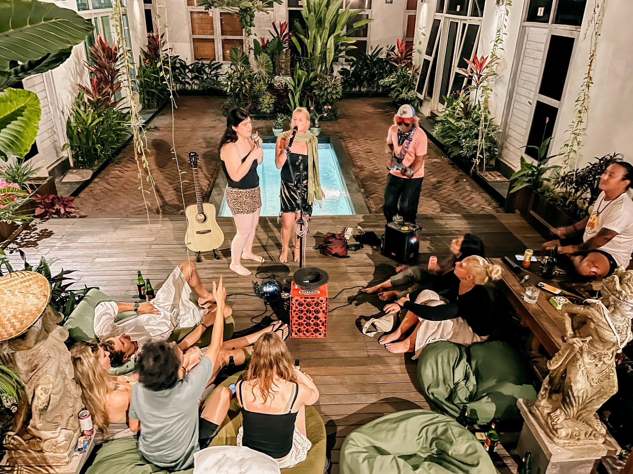 Group of backpackers enjoying live music next to the pool