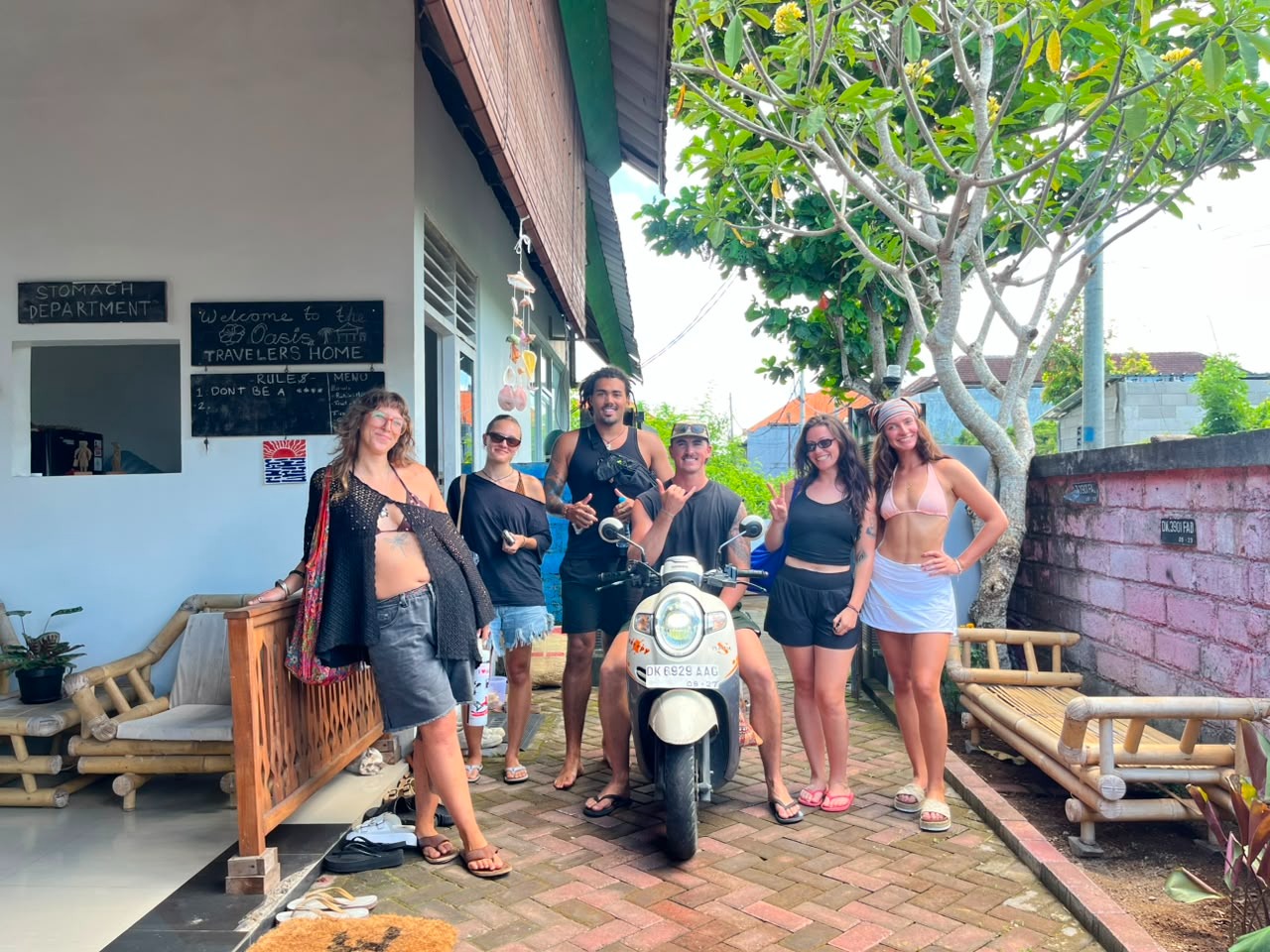 Group of backpackers taking a group picture with one on a motorcycle.